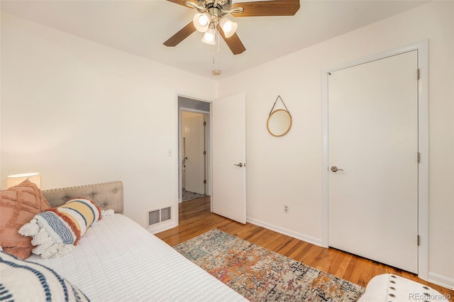 bedroom with ceiling fan, wood finished floors, visible vents, and baseboards