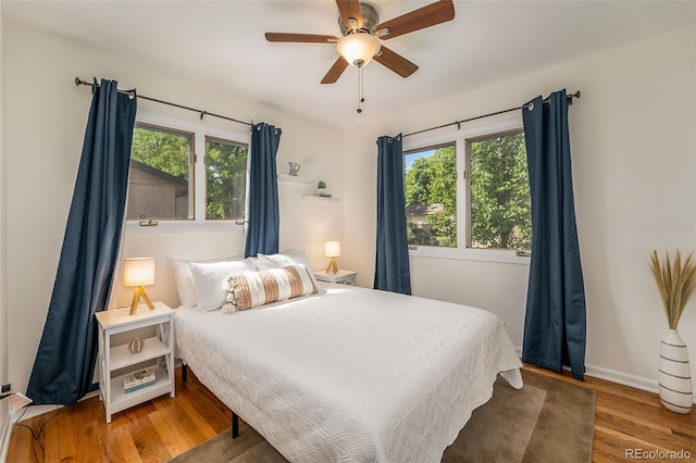 bedroom with a ceiling fan, baseboards, and wood finished floors