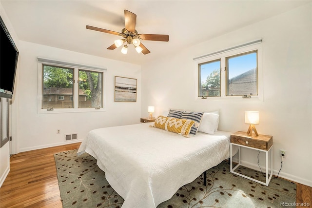 bedroom featuring a ceiling fan, light wood-type flooring, visible vents, and baseboards