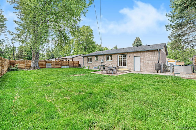 rear view of property with a yard, brick siding, a patio area, and a fenced backyard