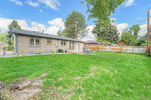 back of house featuring a lawn, a fenced backyard, a gate, a patio area, and brick siding