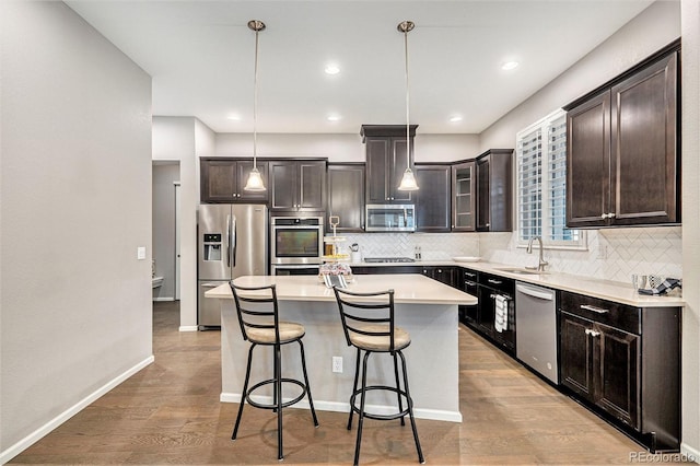 24943 E Phillips Pl, Aurora, CO 80016 - kitchen with stainless steel appliances, a sink, a breakfast bar, tasteful backsplash, and dark brown cabinetry