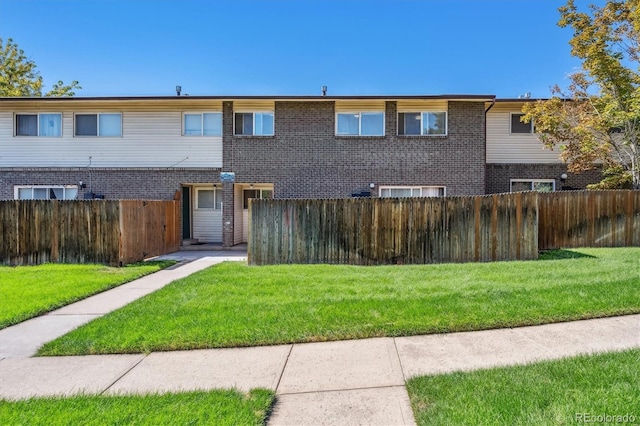 view of front of property with brick siding, fence private yard, and a front lawn