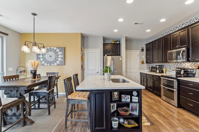 kitchen with decorative light fixtures, sink, dark brown cabinets, and stainless steel appliances