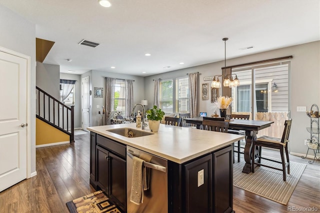 kitchen with dark hardwood / wood-style flooring, stainless steel dishwasher, sink, decorative light fixtures, and an island with sink