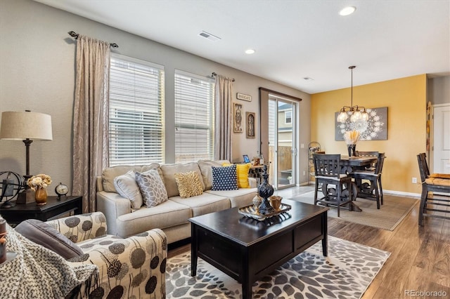 living room with a chandelier, light hardwood / wood-style floors, and plenty of natural light