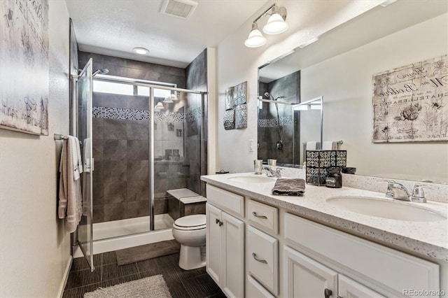 bathroom with a textured ceiling, vanity, an enclosed shower, and toilet