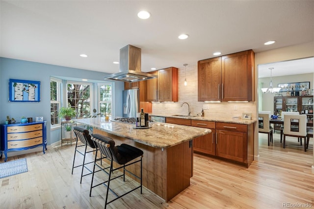 16268 E Belleview Dr, Centennial, CO 80015 - kitchen with island exhaust hood, stainless steel appliances, brown cabinetry, a kitchen bar, and light wood finished floors