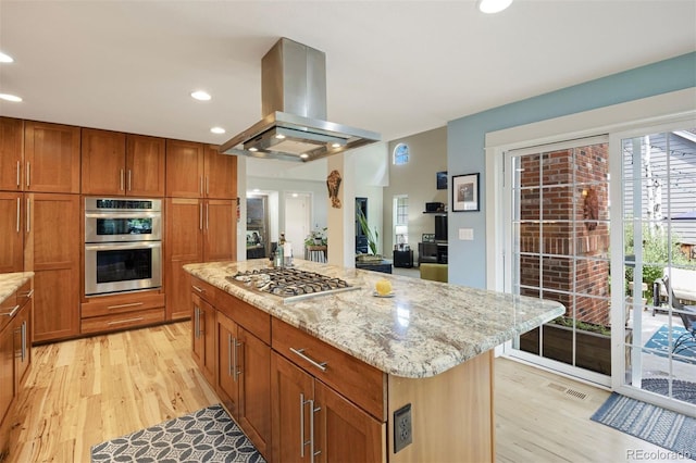 16268 E Belleview Dr, Centennial, CO 80015 - kitchen with island exhaust hood, stainless steel appliances, light wood-style floors, light stone countertops, and brown cabinets