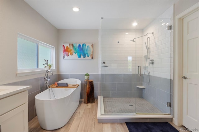 16268 E Belleview Dr, Centennial, CO 80015 - bathroom with tile walls, a shower stall, a freestanding bath, wood finished floors, and vanity
