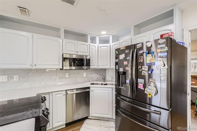 kitchen featuring appliances with stainless steel finishes, light wood-type flooring, white cabinetry, and sink