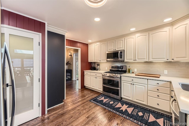 2684 S Adams St, Denver, CO 80210 - kitchen featuring appliances with stainless steel finishes, backsplash, dark wood-type flooring, light countertops, and white cabinetry