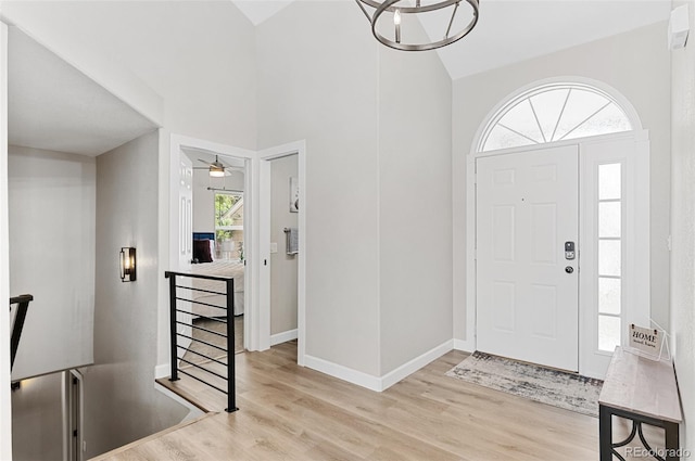 foyer entrance with ceiling fan, high vaulted ceiling, and light hardwood / wood-style flooring