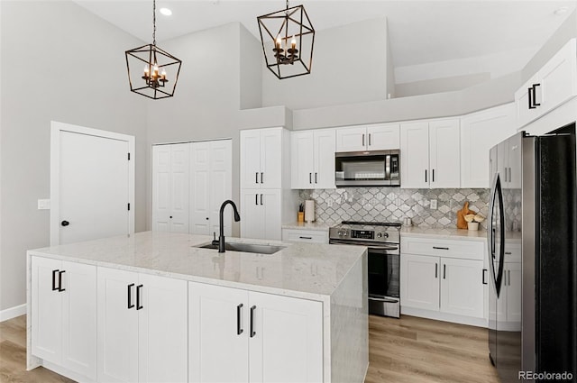 kitchen with appliances with stainless steel finishes, decorative backsplash, light wood-type flooring, and light stone countertops