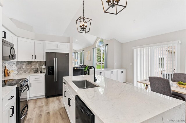 kitchen with backsplash, light hardwood / wood-style floors, sink, black appliances, and vaulted ceiling