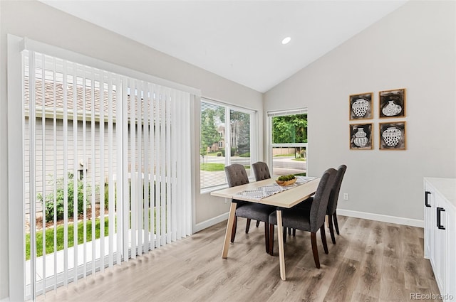 dining room with high vaulted ceiling and light wood-type flooring