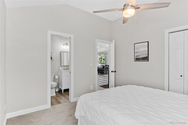 bedroom with ensuite bath, a closet, vaulted ceiling, ceiling fan, and light colored carpet