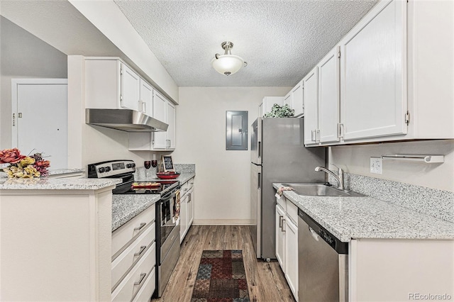 kitchen featuring stainless steel appliances, under cabinet range hood, a sink, light wood-style floors, and a textured ceiling