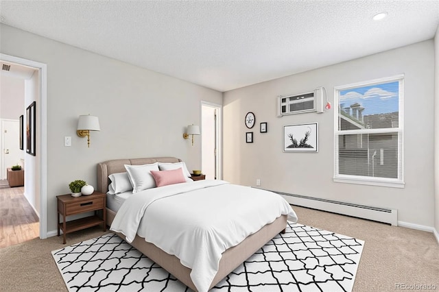 bedroom with a baseboard heating unit, light colored carpet, a textured ceiling, baseboards, and a wall unit AC