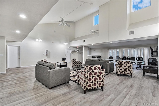 living room with wood finished floors, a ceiling fan, baseboards, a towering ceiling, and recessed lighting