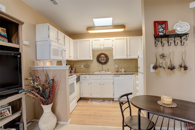 kitchen featuring backsplash, white cabinets, light wood-type flooring, and white appliances