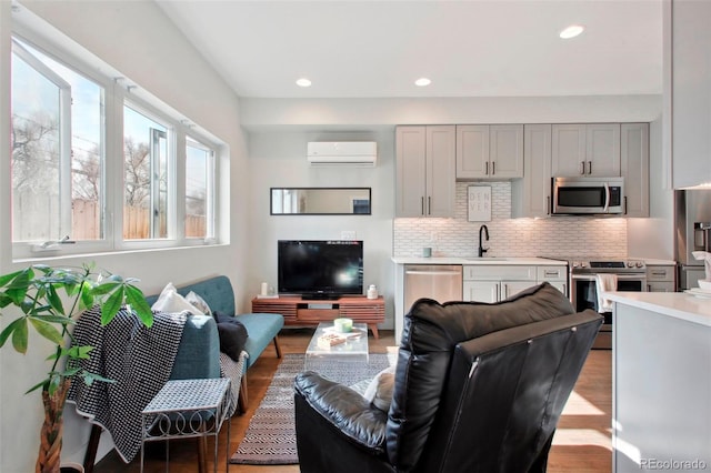 living room featuring sink, a wall mounted AC, and light wood-type flooring