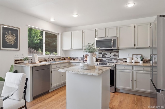 20396 E Berry Pl, Centennial, CO 80015 - kitchen with stainless steel appliances, decorative backsplash, a kitchen island, light stone counters, and light wood finished floors