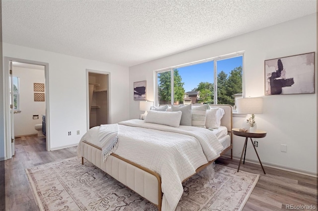 20396 E Berry Pl, Centennial, CO 80015 - bedroom featuring light wood-type flooring, a textured ceiling, a walk in closet, and connected bathroom