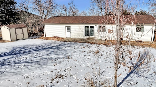 snow covered back of property with a storage shed