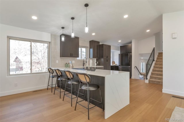 kitchen with a breakfast bar area, light countertops, dark brown cabinetry, a peninsula, and fridge