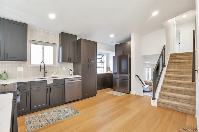 kitchen with stainless steel appliances, a wealth of natural light, a sink, and light wood finished floors