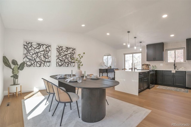 dining space featuring vaulted ceiling, light wood-style flooring, and recessed lighting