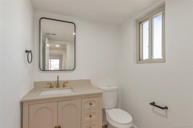 bathroom with visible vents, vanity, and toilet