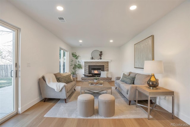 living room with light wood-style flooring, visible vents, and recessed lighting