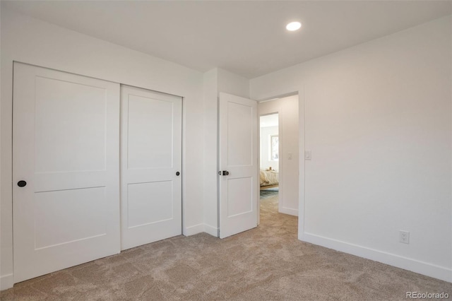 unfurnished bedroom with a closet, recessed lighting, carpet flooring, and baseboards