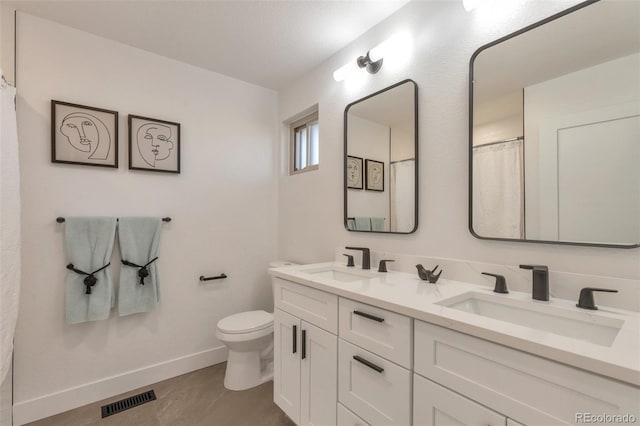 bathroom featuring toilet, a sink, visible vents, and baseboards