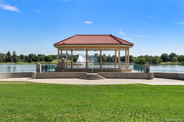 view of dock with a water view, a gazebo, and a lawn