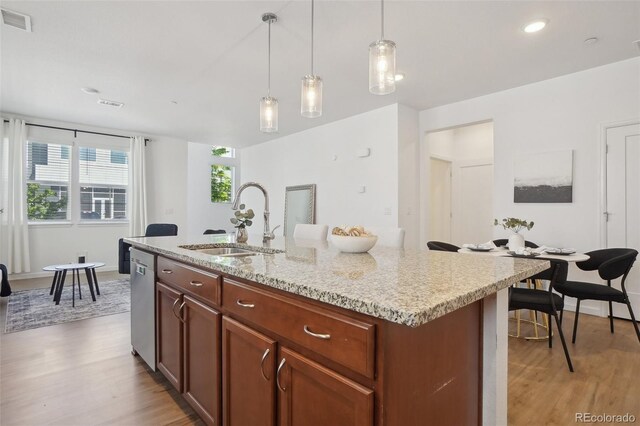1743 Spring Water Pt, Colorado Springs, CO 80908 - kitchen featuring a sink, dishwasher, light wood-style flooring, decorative light fixtures, and a center island with sink