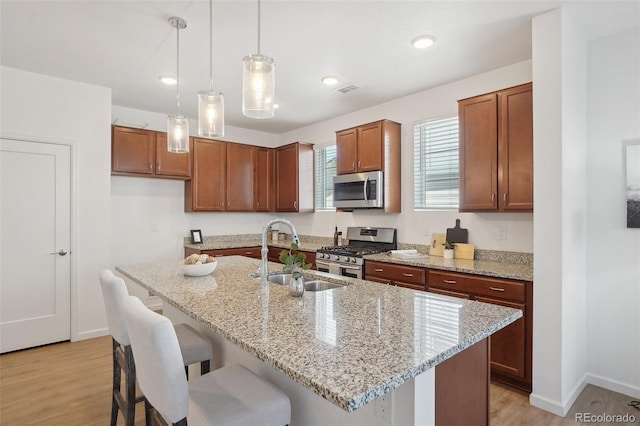 1743 Spring Water Pt, Colorado Springs, CO 80908 - kitchen with appliances with stainless steel finishes, a sink, light wood-style flooring, a kitchen bar, and baseboards
