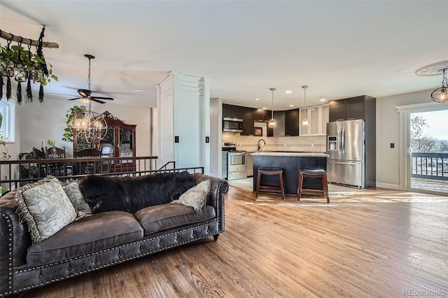 living room featuring ceiling fan, sink, and light hardwood / wood-style flooring