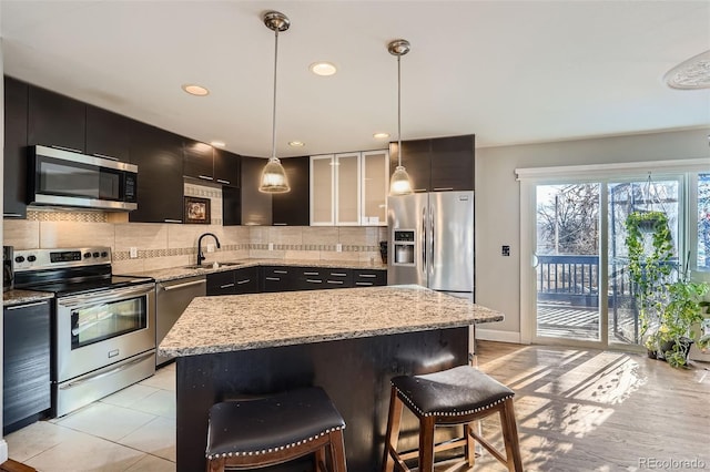 kitchen with sink, a center island, hanging light fixtures, a kitchen breakfast bar, and appliances with stainless steel finishes