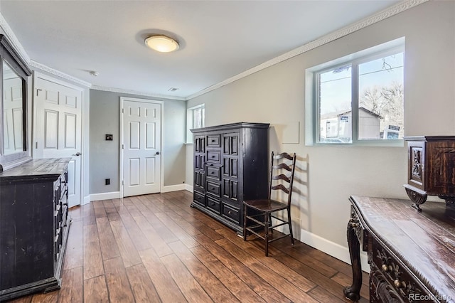 sitting room with ornamental molding and dark wood-type flooring