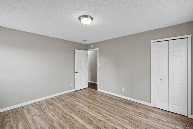 unfurnished bedroom with a textured ceiling, light wood-type flooring, and a closet