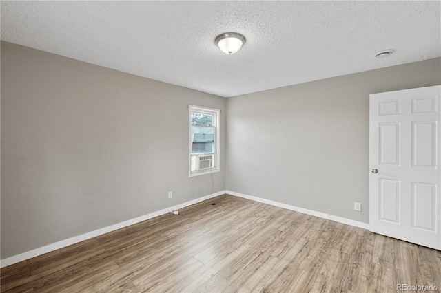 spare room featuring a textured ceiling and light hardwood / wood-style flooring