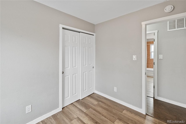 unfurnished bedroom featuring light wood-type flooring and a closet