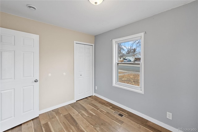 unfurnished bedroom featuring multiple windows, a closet, and hardwood / wood-style floors