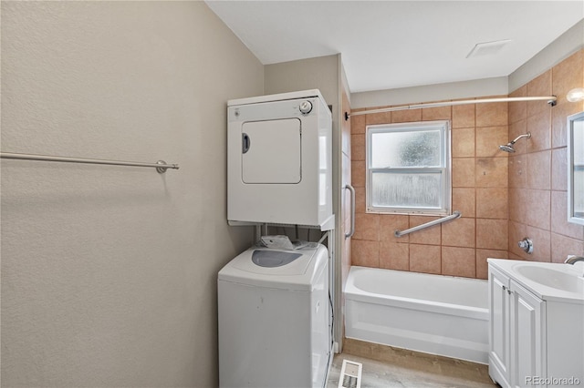 bathroom with vanity, tiled shower / bath, and stacked washer and clothes dryer