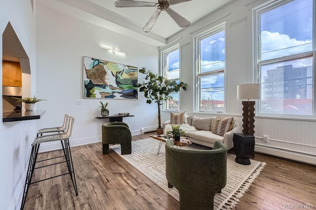 living area featuring wood-type flooring, baseboards, a baseboard radiator, a baseboard heating unit, and a ceiling fan