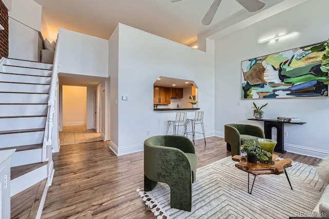 living room with baseboards, a ceiling fan, stairs, and wood finished floors
