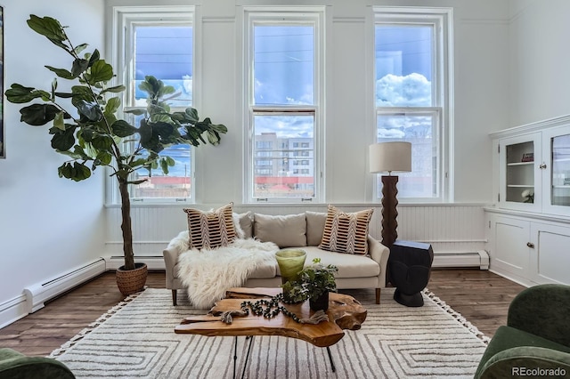 sitting room featuring wood finished floors, baseboard heating, and a wealth of natural light